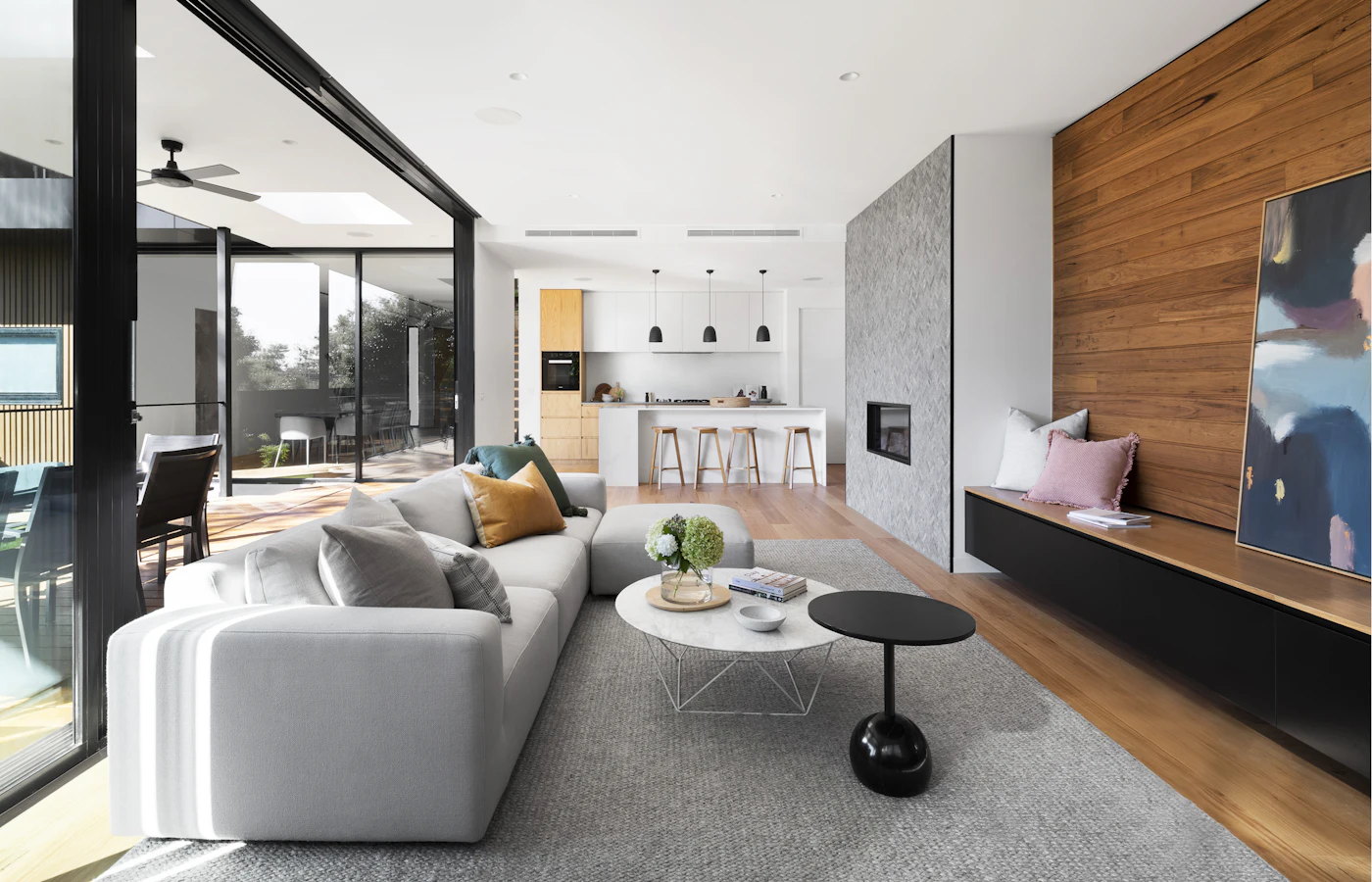 After: bright open living room with white sofa, timber feature wall and styled coffee table