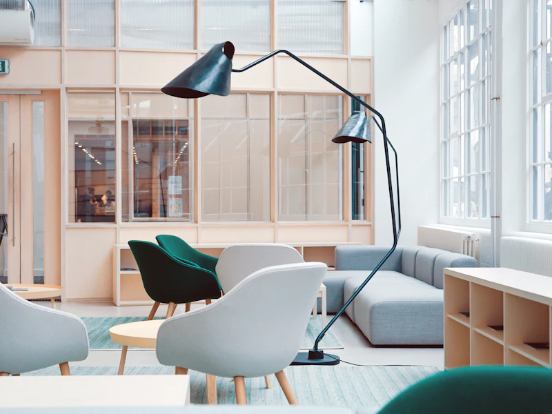 Bright co-working lounge with white shell chairs, a teal sofa and black floor lamps